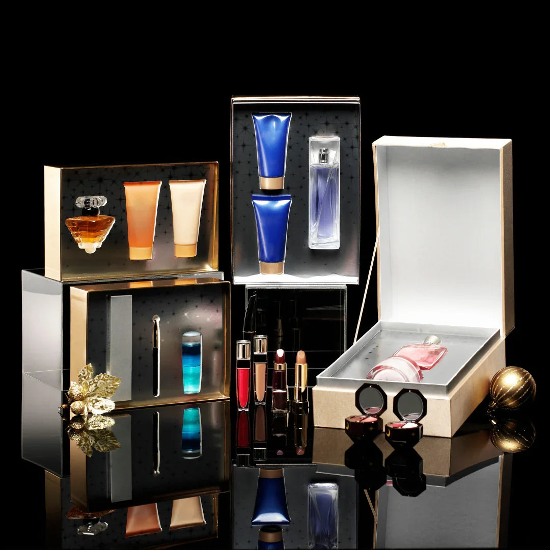 Luxury perfume and skincare gift sets in elegant packaging on a black reflective surface.